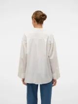 Camisa blanca oversize de manga larga con cuello clásico, puños abotonados y cierre frontal de botones.