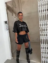 Minifalda negra de jean con tablas, abertura lateral y cinturón con hebilla metálica.