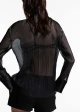 Camisa negra semitransparente de tejido fluido con ribetes satinados, cuello camisero, cierre de botones y mangas largas abotonadas.