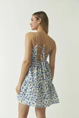 Vestido corto con estampado de orquídeas color beige sobre fondo negro, con breteles finos y corte evasé.