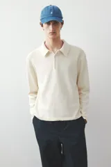 Remera polo de punto fino color crema, de manga larga con puños y bajo acanalados.