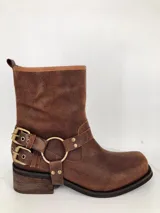 Bota corta de cuero color marrón, con hebillas doradas y estribo desmontable.