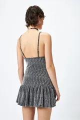 Vestido corto de lurex plateado y negro, sin mangas, con breteles finos regulables y volados tipo balloon desde la cadera.