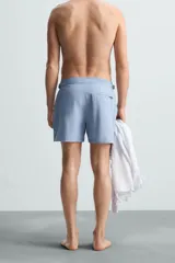 Short de baño celeste de tejido técnico con cintura elástica ajustable con cordón interior y trabillas laterales. Tiene bolsillos frontales y bolsillo trasero con cierre de cremallera. Cuenta con forro interior y cierre frontal con cremallera y botón a presión oculto.