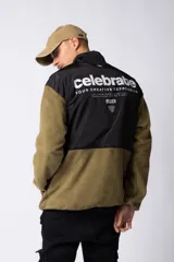 Campera negra con la parte superior de tela tipo rompevientos con dos bolsillos con solapa y la parte inferior de micro polar. Tiene cierre frontal y cuello alto.