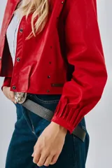 Campera bomber corta de cuero color rojo, con cuello clásico, cierre frontal con botones a presión y mangas largas con puños fruncidos. Tiene dos bolsillos laterales y etiqueta con el logo de la marca en el ruedo.