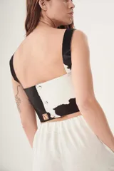 Top corto de cuero ovino con estampado de vaca en blanco y negro, con breteles anchos.