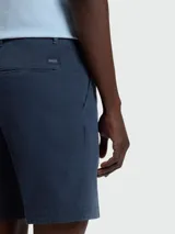 Shorts de vestir para hombre, color azul marino, de corte recto y largo por encima de la rodilla. Presenta cierre frontal con botón y cremallera, y bolsillos laterales y traseros.