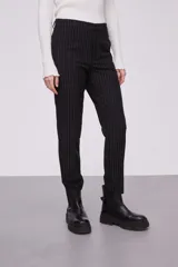 Pantalón negro a rayas verticales blancas, de corte skinny.