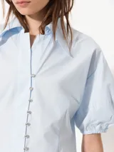 Camisa negra de popelina, de silueta amplia y diseño liviano. Incluye cuello clásico y cierre frontal con botones.