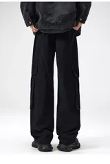 Pantalón cargo negro de corte ancho, confeccionado en gabardina de algodón. Presenta cintura elástica y regulable con cordón blanco, y múltiples bolsillos cargo laterales con costuras destacadas.