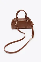 Bolso mini tipo bowling color negro, con doble compartimento con cierre de cremallera, asa de mano y asa bandolera extraíble.