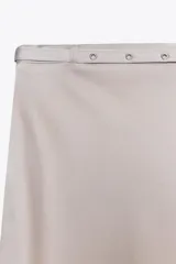 Falda midi de tiro alto confeccionada en tejido satinado color gris topo. Cintura con cinturón a tono ajustable con hebilla metálica.