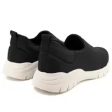 Championes negros de Usaflex, estilo slip-on, con capellada de tejido elástico y suela chunky blanca.