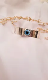 Brazalete rígido plateado con un dije de ojo turco en el centro.
