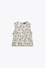 Top sin mangas con estampado de flores blancas y negras, cuello redondo, corte peplum y cierre con botón en la espalda.