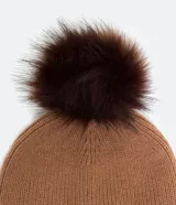 Gorro de lana acrílica color marrón con pompón de piel sintética en la parte superior y dobladillo acanalado.