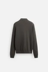 Polo de hombre color gris oscuro, de punto ligero tejido en hilatura con mezcla de seda y algodón. Tiene cuello solapa con cierre frontal de botonadura, manga larga y acabados en rib.