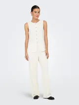 Chaleco corto color blanco hueso con cuello abierto y cierre frontal con botones. Confeccionado en tejido de punto con mezcla de poliéster y elastano. Diseño sin mangas con textura suave y calce ajustado.