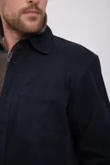 Camisa negra de manga larga con cuello clásico y cierre frontal con botones. Tiene un bolsillo de parche en el pecho izquierdo.