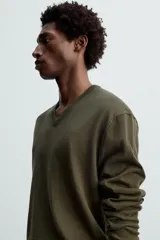 Jersey verde oscuro de punto fino, con cuello en V y mangas largas.