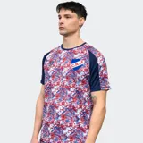Remera de fútbol Umbro del Club Nacional de Football, modelo Pro Training Active. Diseño con estampado abstracto en blanco, rojo y azul, con mangas cortas raglán en azul marino y escudo del club en el pecho.