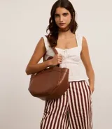 Bolso shopper grande color marrón, con costuras contrastantes, asa de mano y asa larga. Incluye bolsillo interno desmontable.