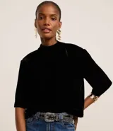 Blusa boxy de terciopelo negro con cuello alto y mangas cortas amplias.