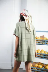 Vestido corto negro con patrón calado cuadrado, cuello redondo y mangas cortas con terminaciones a contratono en blanco.