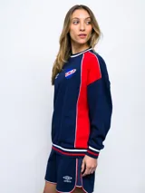 Buzo de felpa azul marino con mangas raglán rojas y detalles tricolor en puños, mangas y cuello. Incluye logo de Umbro bordado en el pecho y escudo del Club Nacional de Football.