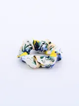 Colero de tela con estampado floral en tonos azul, amarillo, verde y beige sobre fondo blanco.