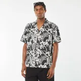 Camisa de manga corta con estampado de flores y hojas en blanco y negro, con cuello solapa y cierre frontal con botones de madera.