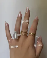 Set de tres anillos dorados: uno con una perla barroca grande y una perla pequeña, otro con forma de onda y otro doble.