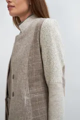 Chaqueta corta color marrón con cuello solapa y diseño con patchwork de telas. Manga larga con detalle de coderas aplicadas. Cierre frontal mediante botones y bolsillos ojal. Con forro.