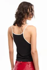 Musculosa negra de jersey de algodón con modal peruano, de calce fitted, escote en "U" y largo a la cadera. Presenta detalle de breteles y escote a contratono en blanco. Cuenta con bordado marcario a contratono en frente como distintivo.