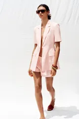 Bermuda de tiro medio color rosa, confeccionada en lino, con bolsillos delanteros y falsos bolsillos de vivo en la espalda.