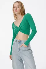 Top corto tejido color verde esmeralda, de manga larga y escote en V con detalle de nudo en el centro.
