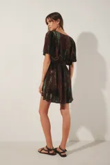 Vestido corto con escote en V y mangas cortas amplias, con elástico fruncido en la cintura. Presenta un teñido tie-dye en tonos marrón oscuro y verde azulado, con bordado de hilos de lurex en el escote.