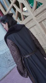 Abrigo largo marrón con mangas de cuero acolchado, cuello de piel sintética y cinturón de cuero.