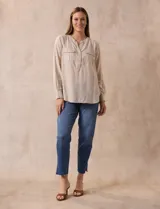 Blusa beige de lino y rayón, marca Dash. Tiene cuello a la base, escote en V y abertura con botones. Delantera con bolsillos. Largo de manga regulable con presilla y botón.