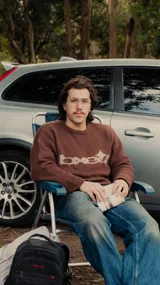 Sweater marrón de tejido de punto con cuello redondo y mangas largas. Presenta un diseño gráfico en color beige en el frente.