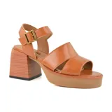 Sandalias de cuero color suela, con plataforma y taco cuadrado de madera. Tiras anchas cruzadas sobre el empeine y pulsera con hebilla metálica.