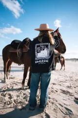 Buzo negro de manga larga con estampa en la espalda con una foto en blanco y negro de una ola y el logo de la marca Glassy.