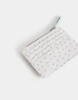 Billetera pequeña de cuerina estampada con flores de colores. Tiene cierre superior con tirador rosa, lazo con broche a presión y compartimentos para tarjetas.
