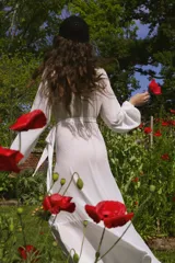 Vestido blanco de crepe con escote en V, mangas largas abullonadas con elástico en los puños, largo irregular, lazo para ajustar en la cintura y volado en el ruedo.