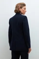 Conjunto de blazer, chaleco y pantalón de vestir de color gris con rayas verticales finas. El blazer es de doble botonadura, el chaleco tiene cuello en V y el pantalón es de corte palazzo.