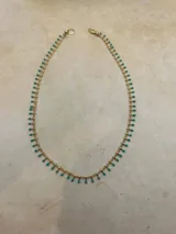 Collar dorado con cadena fina y pequeñas cuentas colgantes.