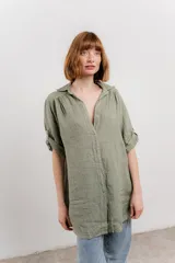 Camisa color beige de lino, con corte recto y calce suelto, cuello camisero, botones en el frente y mangas cortas con presilla y botón.