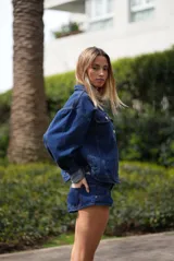 Short de jean azul oscuro, corte micro, con cintura con pasacintos, cierre y botón metálico personalizado. Incluye dos bolsillos delanteros con relojero y remaches, y dos bolsillos traseros clásicos. El lavado artesanal conserva el color índigo intenso del denim.