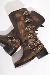 Botas de cuero gastado color marrón con hebillas y apliques de metal de caña alta.